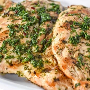 Grilled Chicken topped with chimichurri sauce served on a white platter.