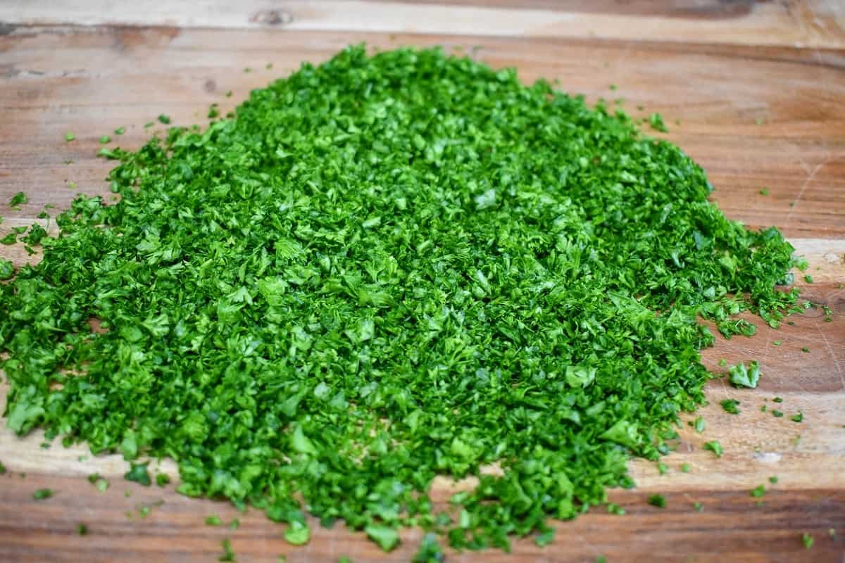 Finely chopped parsley on a wood cutting board.