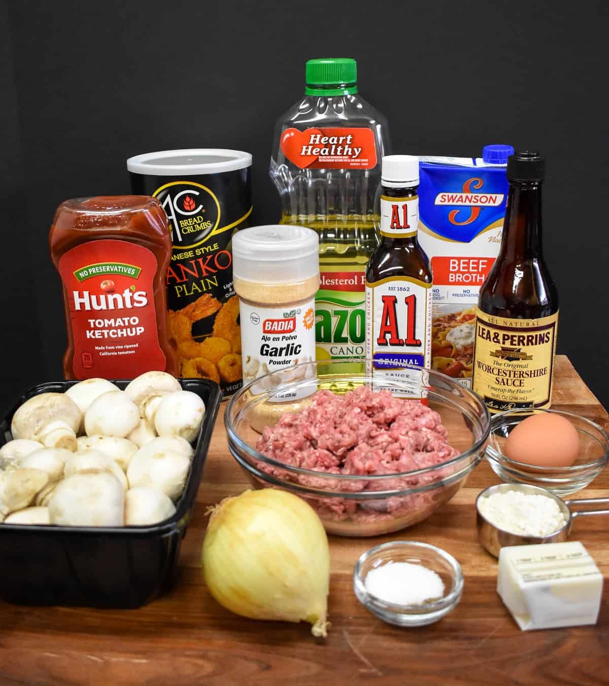 The ingredients for the Salisbury steak meatballs arranged on a large wood cutting board.