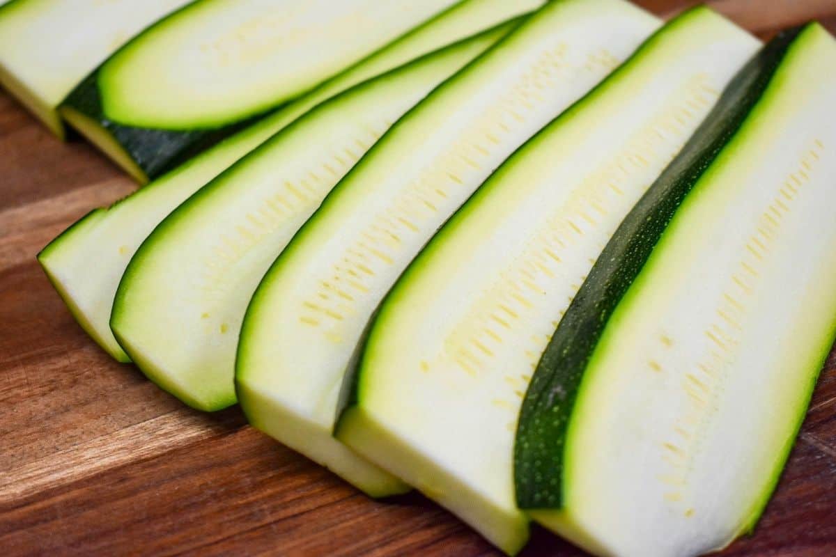 Sliced zucchini on a wood cutting board.