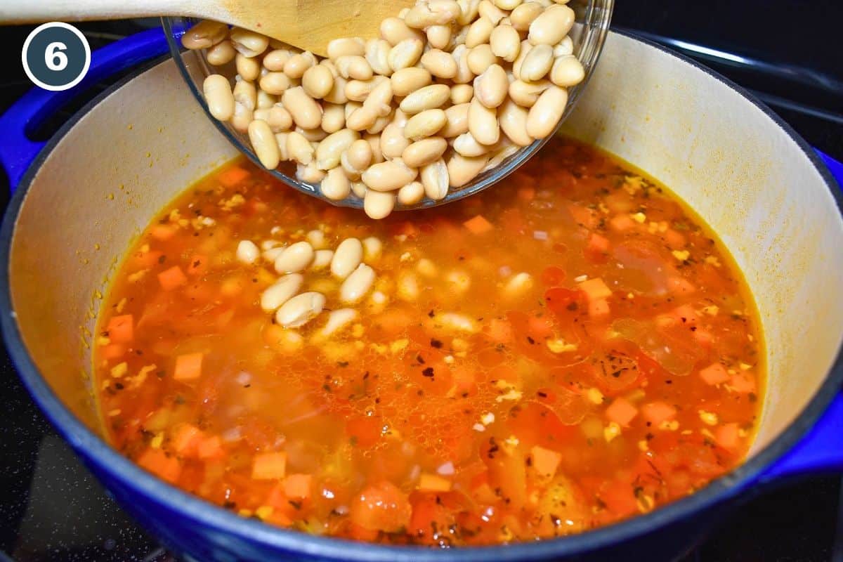 Cannellini beans being added to the sausage and vegetable soup.