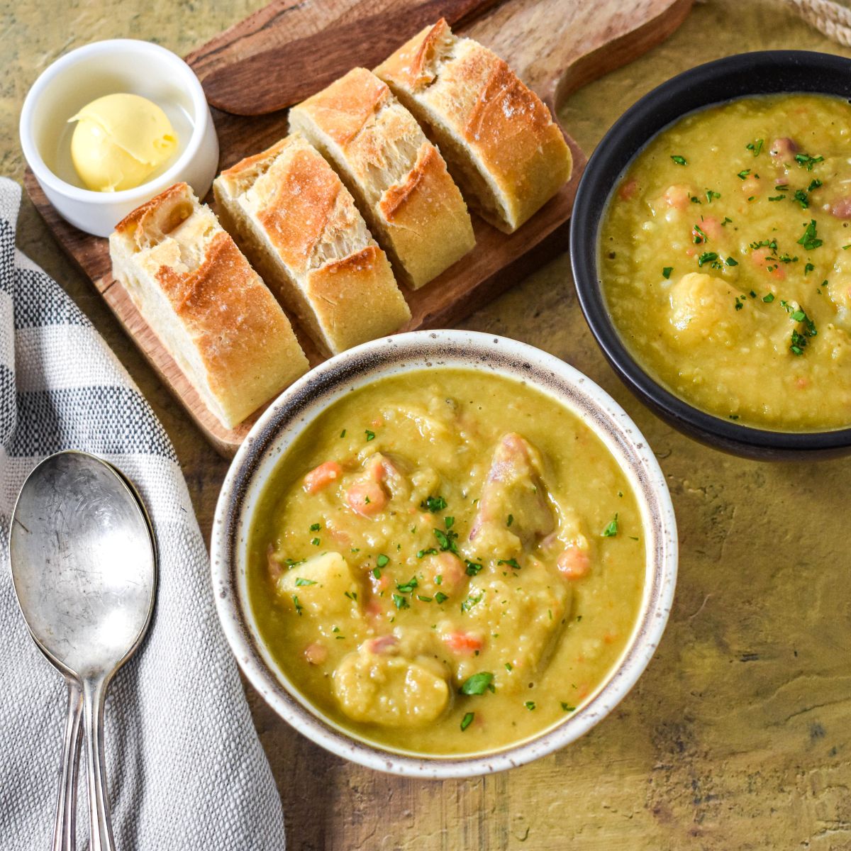 Angled shot of the soup in a white bowl with bread slices and a second bowl in the background.