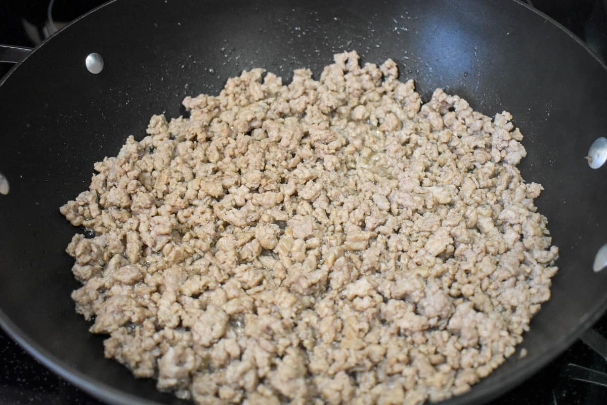 Browned ground pork in a large, black skillet.