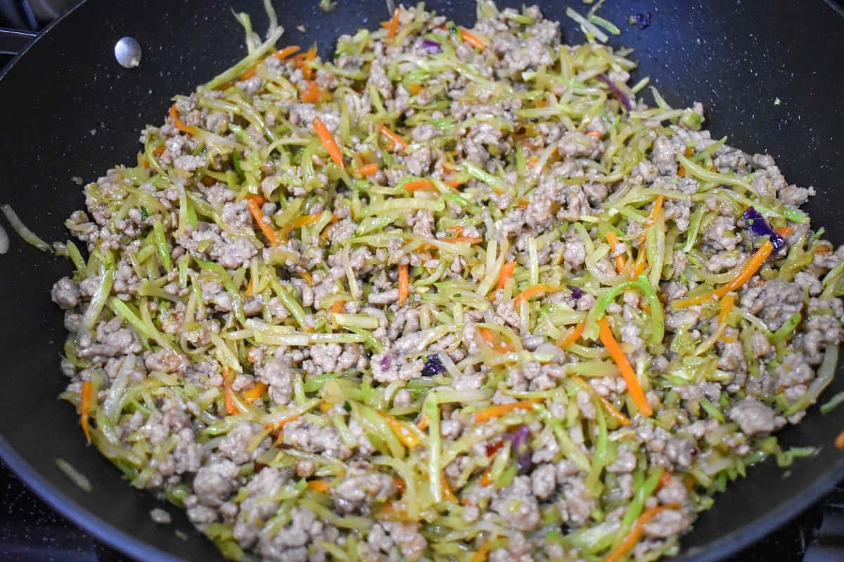 The cooked pork filling mixture in a large, black skillet.