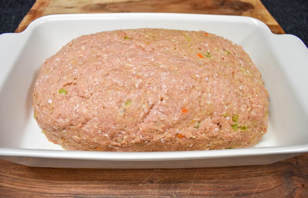 The meat mixture shaped into a loaf in a white baking dish.