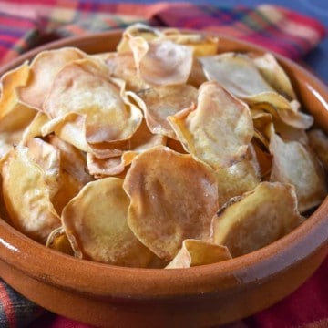 Malanga chips in a terracotta bowl on a red, plaid linen.