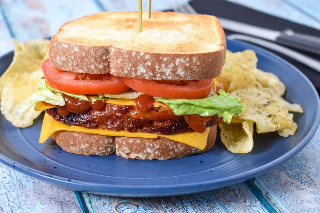 The meatloaf sandwich served on a blue plate with potato chip.s arranged on its sides
