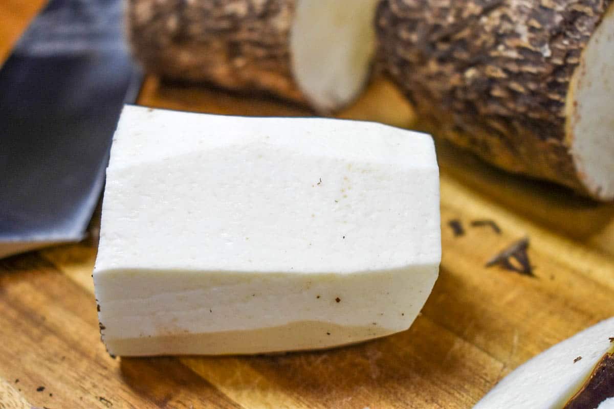 A peeled chunk of malanga on a wood cutting board.