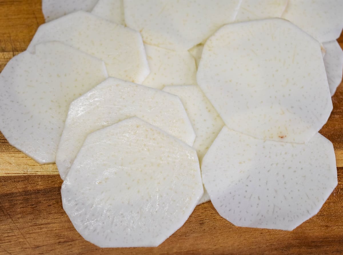 A small mound of thinly sliced rounds on a wood cutting board.