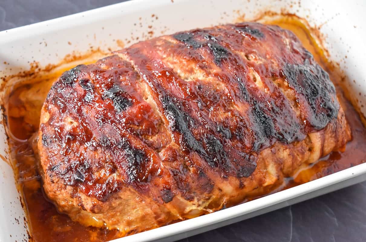 The baked meatloaf in a white baking dish.