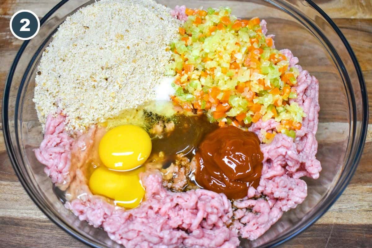 Ground turkey, cooked vegetables, eggs, breadcrumbs, and seasonings in a mixing bowl.