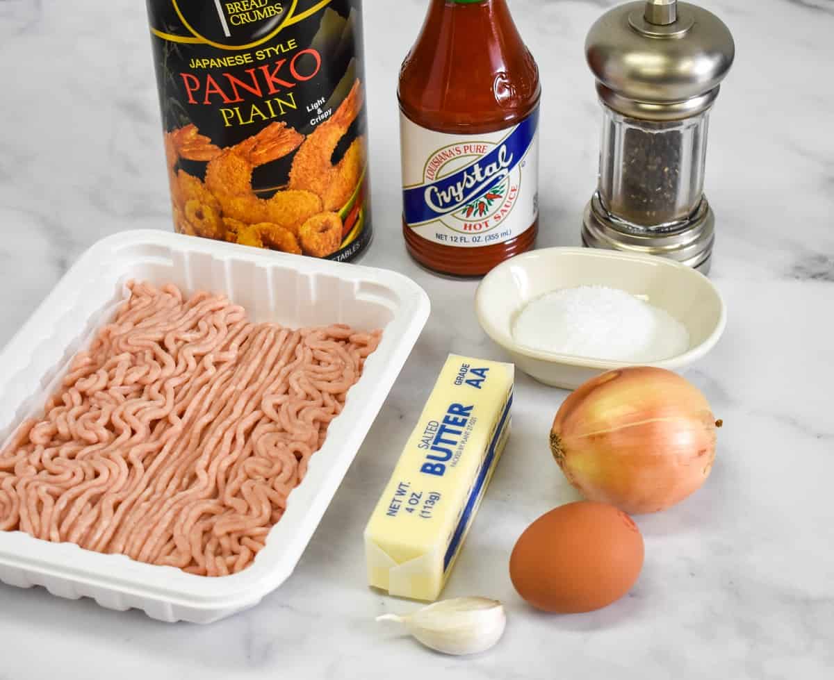 The ingredients for the meatballs arranged on a white table.