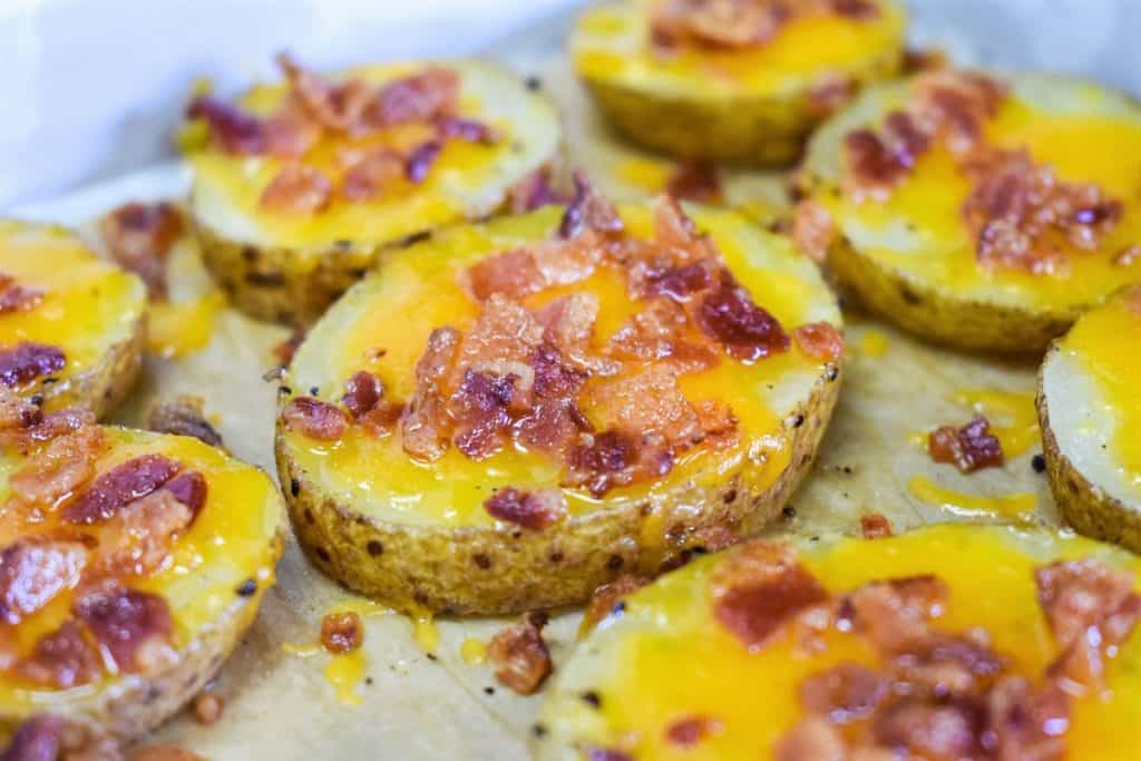 A close up image of the baked potato slices on a parchment paper lined baking sheet.