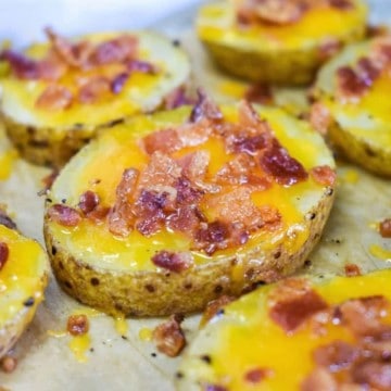 A close up image of the baked potato slices on a parchment paper lined baking sheet.