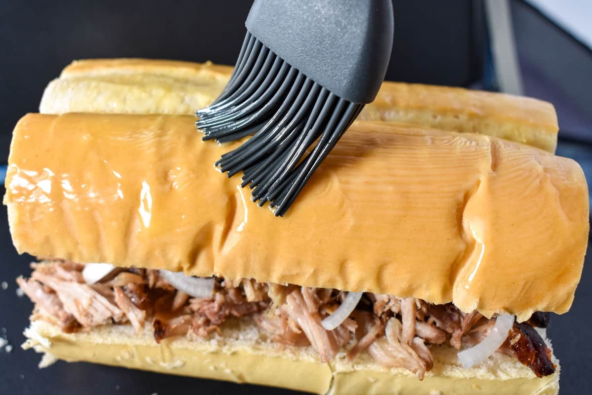 A gray silicone brush applying melted butter on the sandwich.