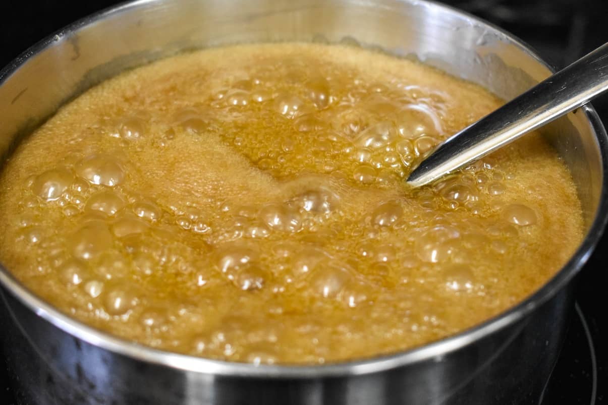 A close-up of the caramel sauce simmering in a saucepan.