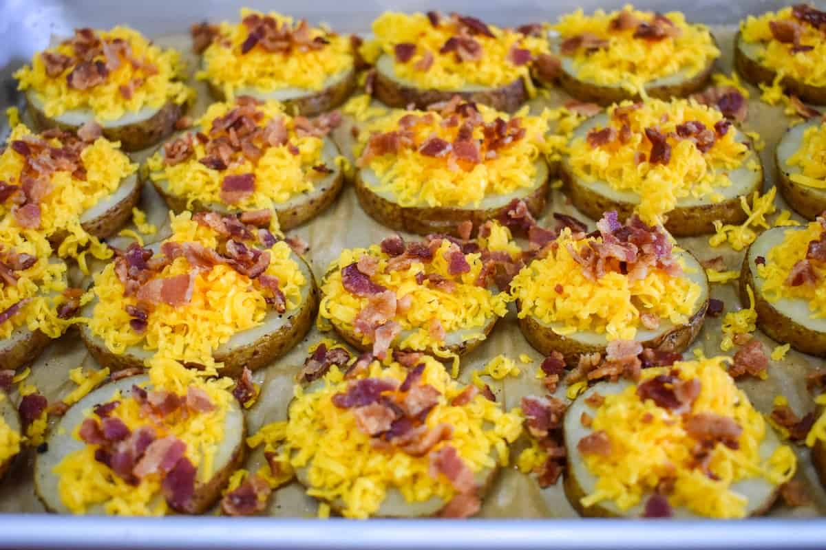 Shredded cheddar cheese and crumbled bacon on the baked potato rounds.