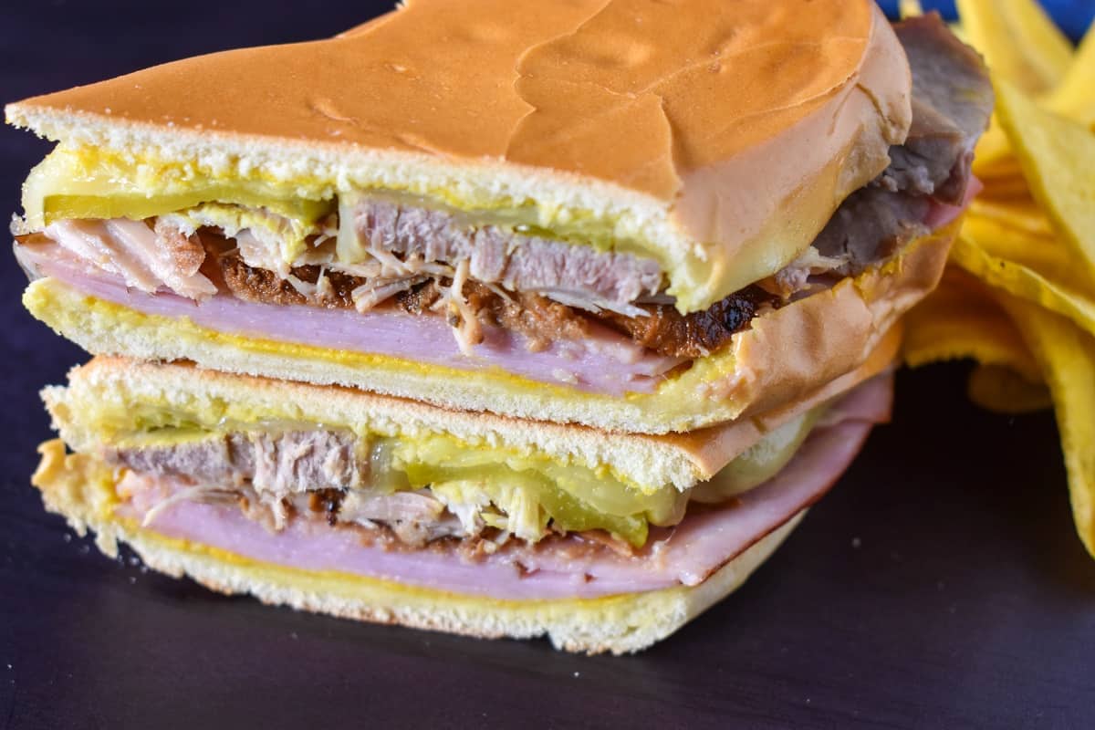 A close up of the sandwich cut in half and stacked with plantain chips on the right side.