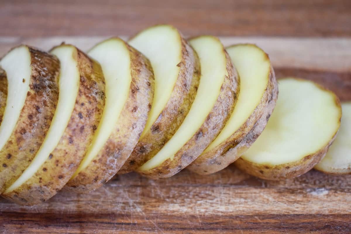 A sliced russet potato on a wood cutting board.