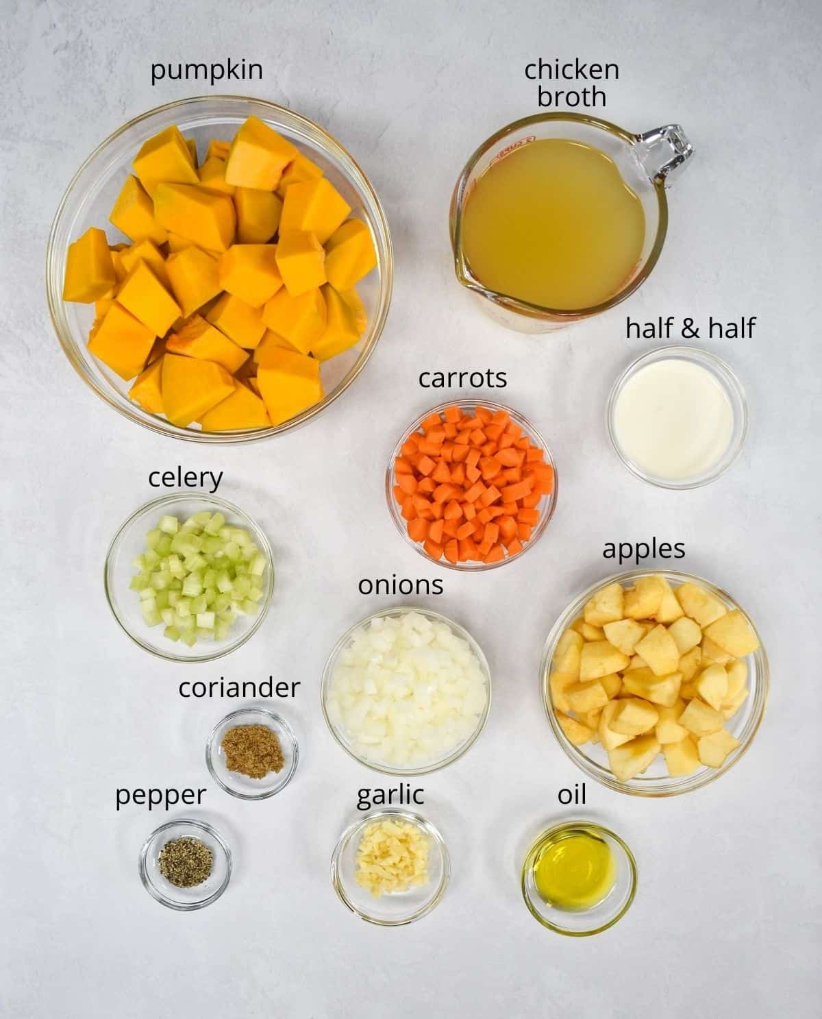 The ingredients for the soup, prepped and arranged in glass bowls on a white table.