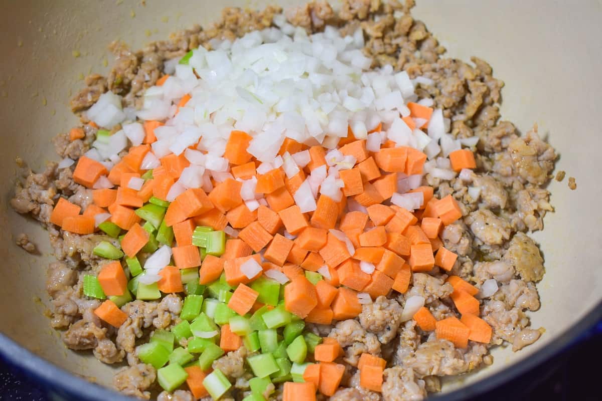 Browned sausage, diced onions, carrots and celery in a large pot.