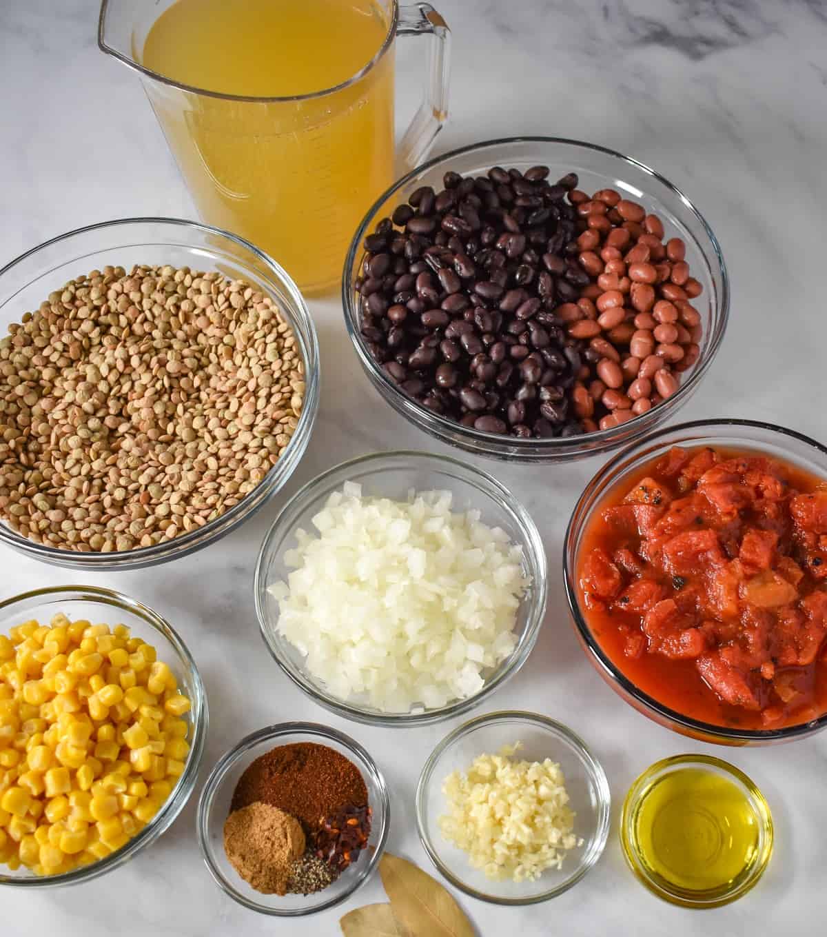 The ingredients prepped and separated into clear, glass bowls and arranged on a white table.