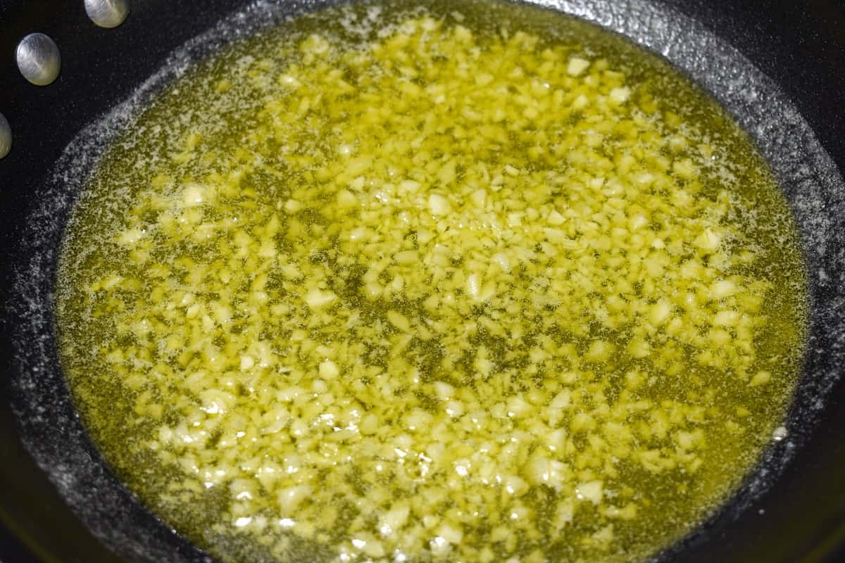 The minced garlic in olive oil in a black skillet.