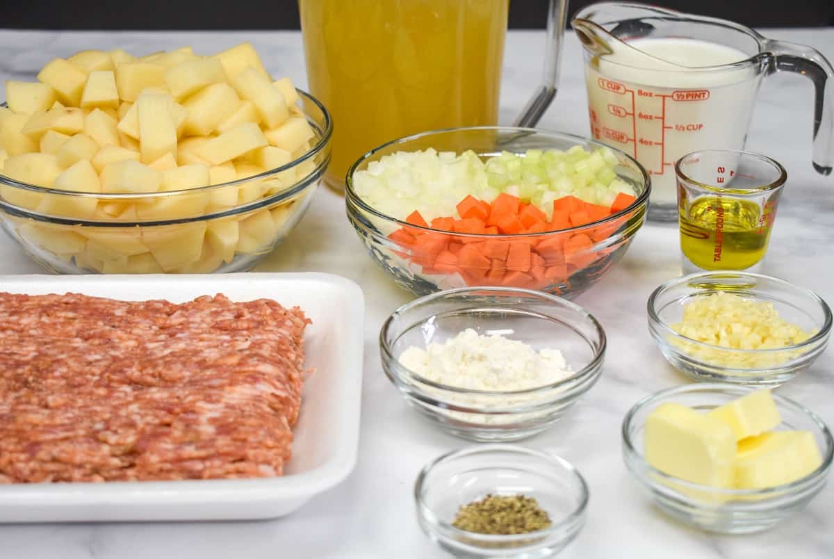 The ingredients for the soup, prepped and separated in glass bowls all arranged on a white table.