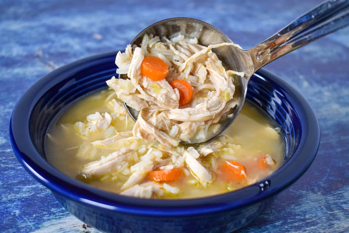 A ladelful of the soup being added to a blue plate.