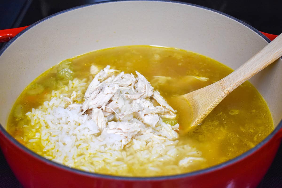 Cooked white rice and shredded chicken added to the simmering soup.