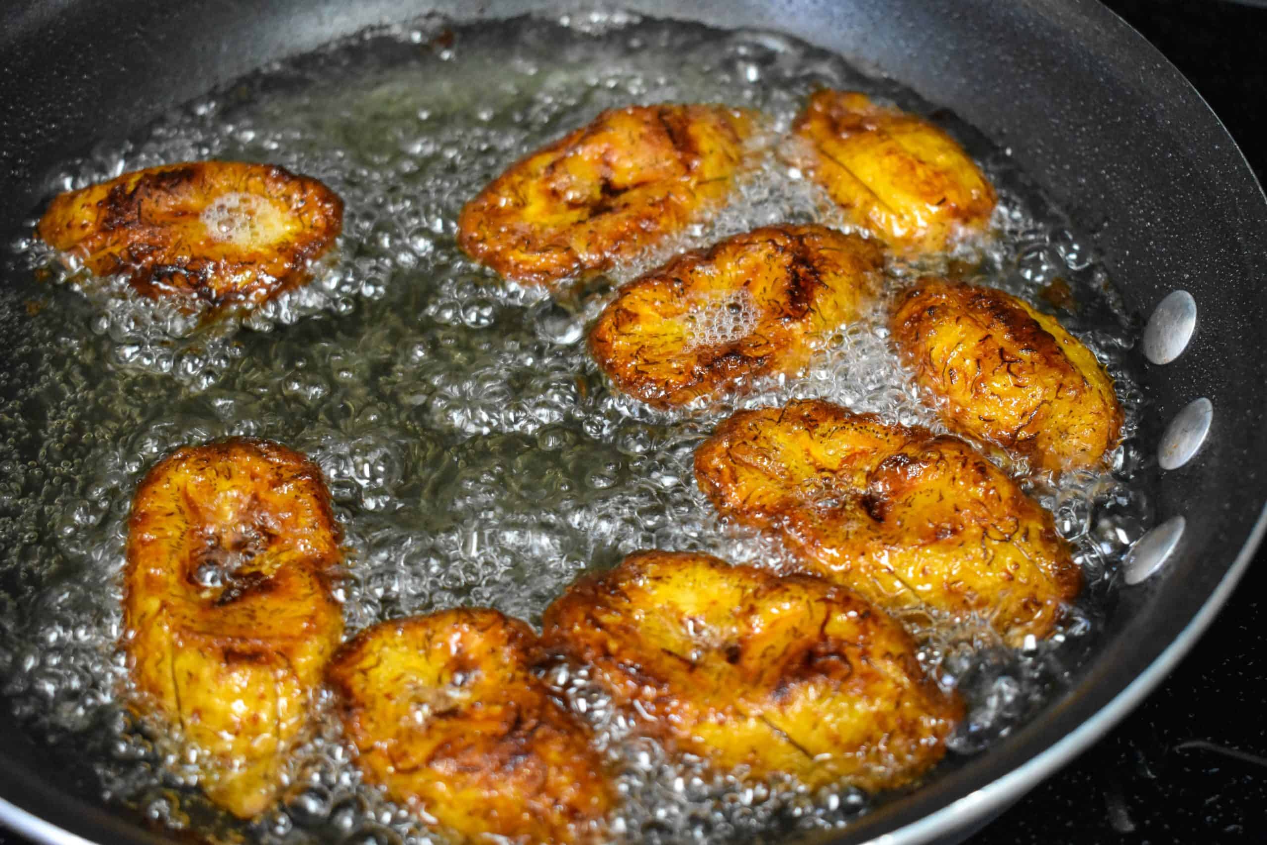 The plantains cooking in they skillet, now browned and caramelized on the edges.