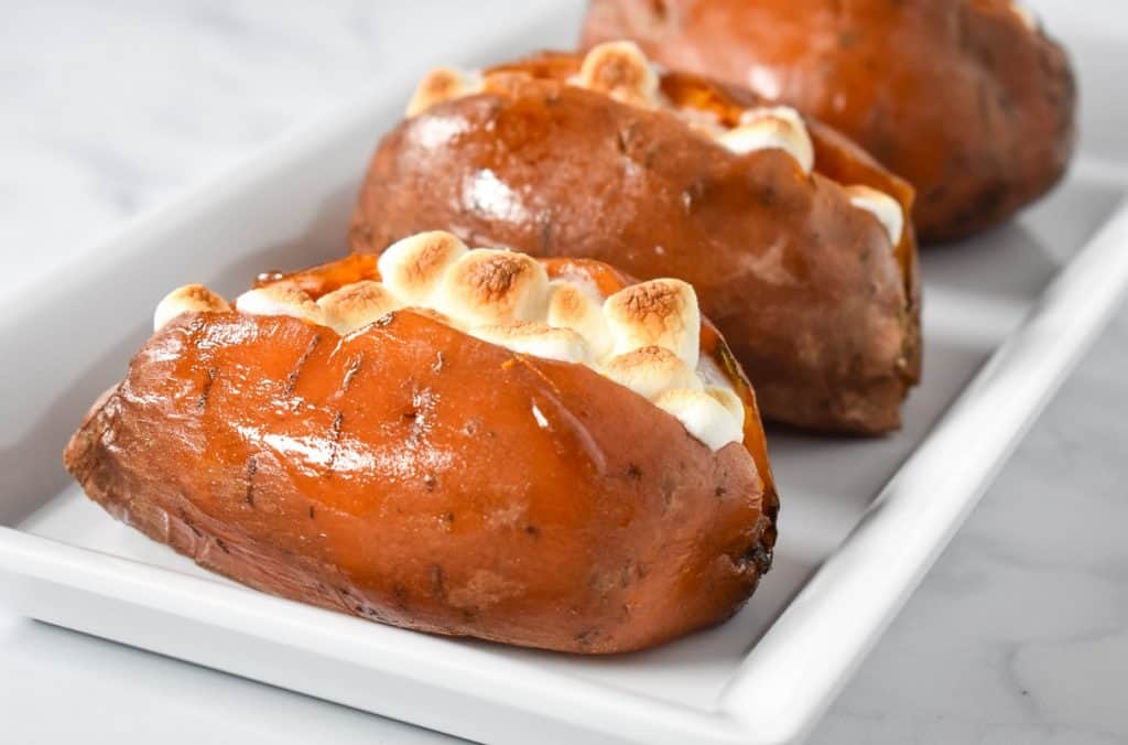 Three of the loaded sweet potatoes arranged on a white platter.