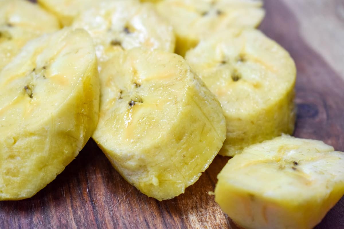 A close up of plantain pieces on a wood cutting board.