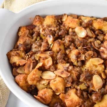 Sausage stuffing in a white casserole dish with a beige linen on the side.