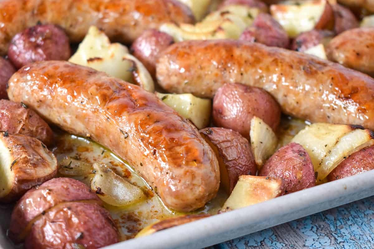 A close up of the sausage and potatoes on the sheet pan.
