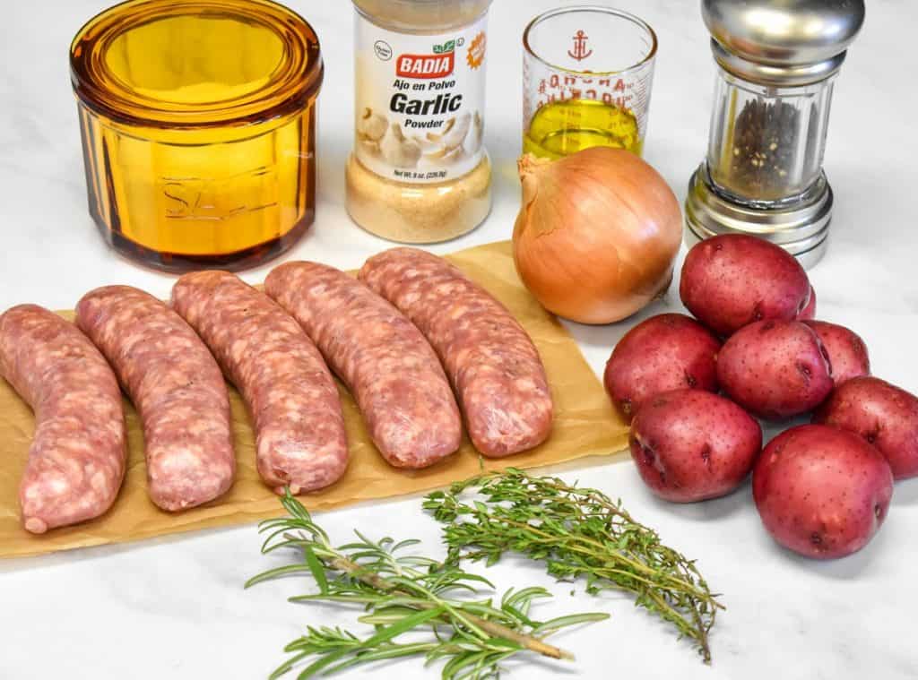 The ingredients for the baked Italian sausage and potatoes arranged on a white table.