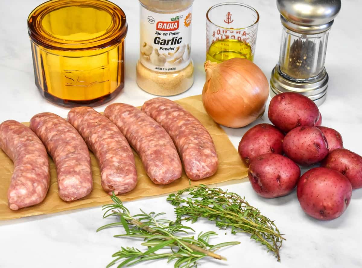The ingredients for the baked Italian sausage and potatoes arranged on a white table.