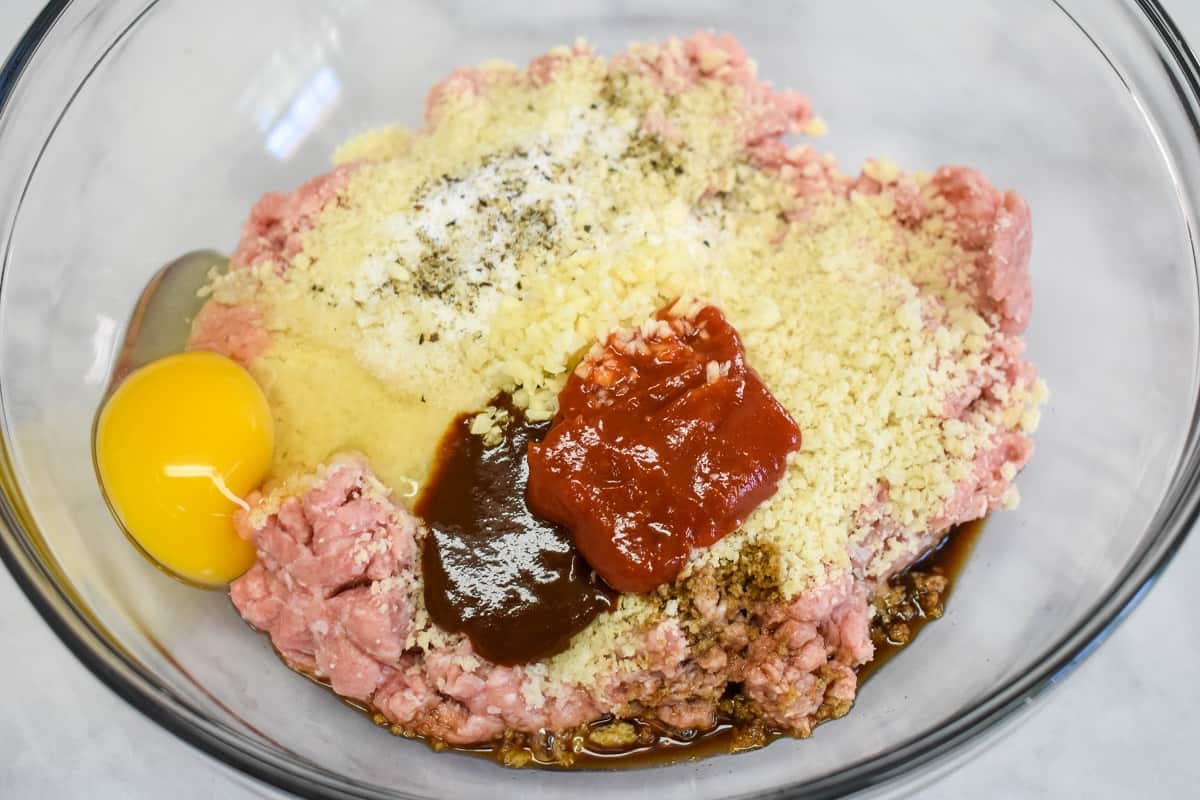 The ingredients for the ground turkey patties added to a large glass bowl but not mixed yet.