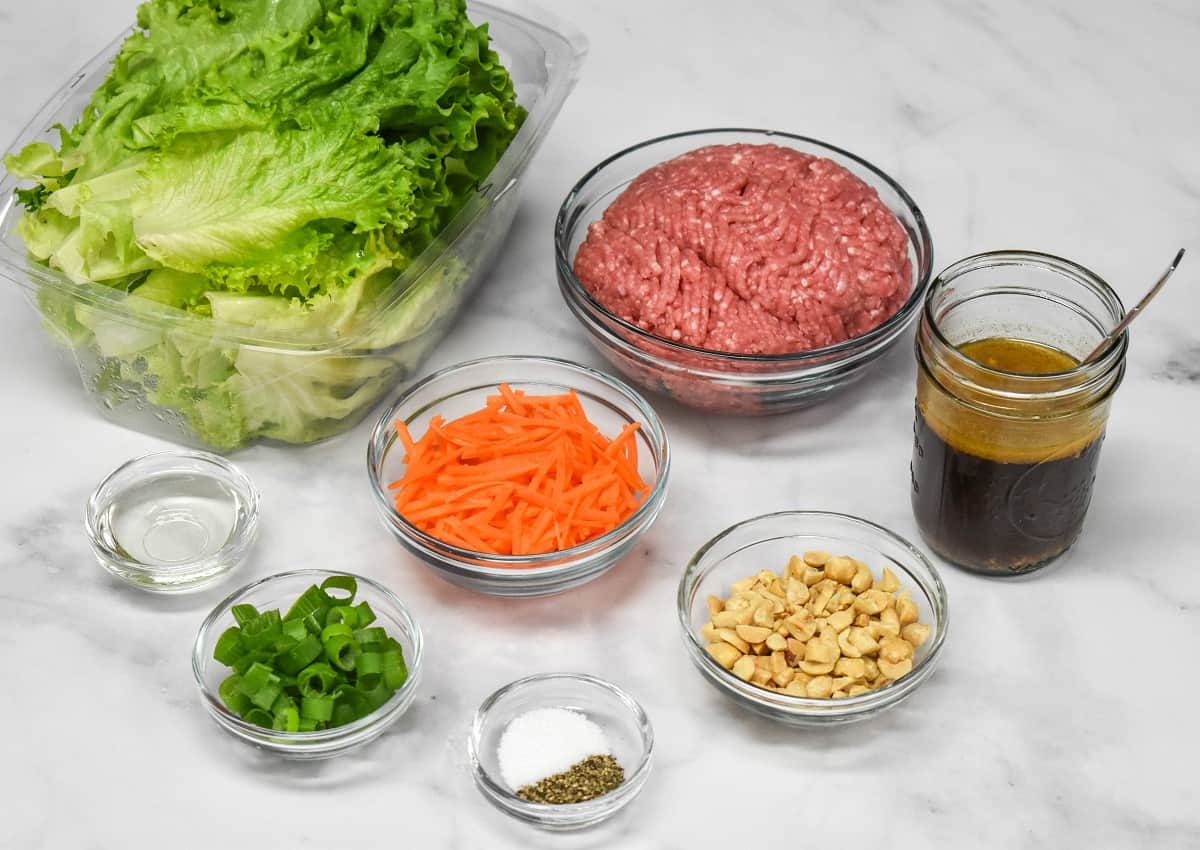 The prepped ingredients for the wraps arranged on a white table in glass bowls.