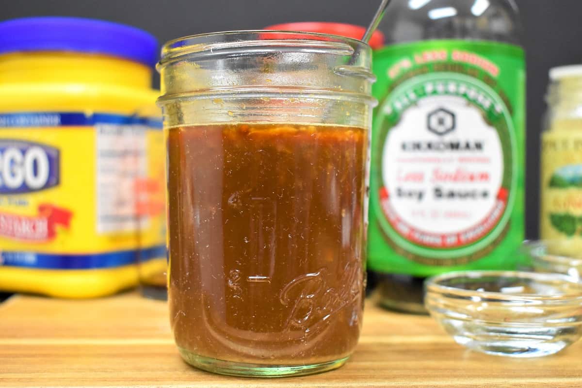 A small jar with the stir fry sauce. The ingredients for the sauce like the soy sauce and cornstarch are in the background.