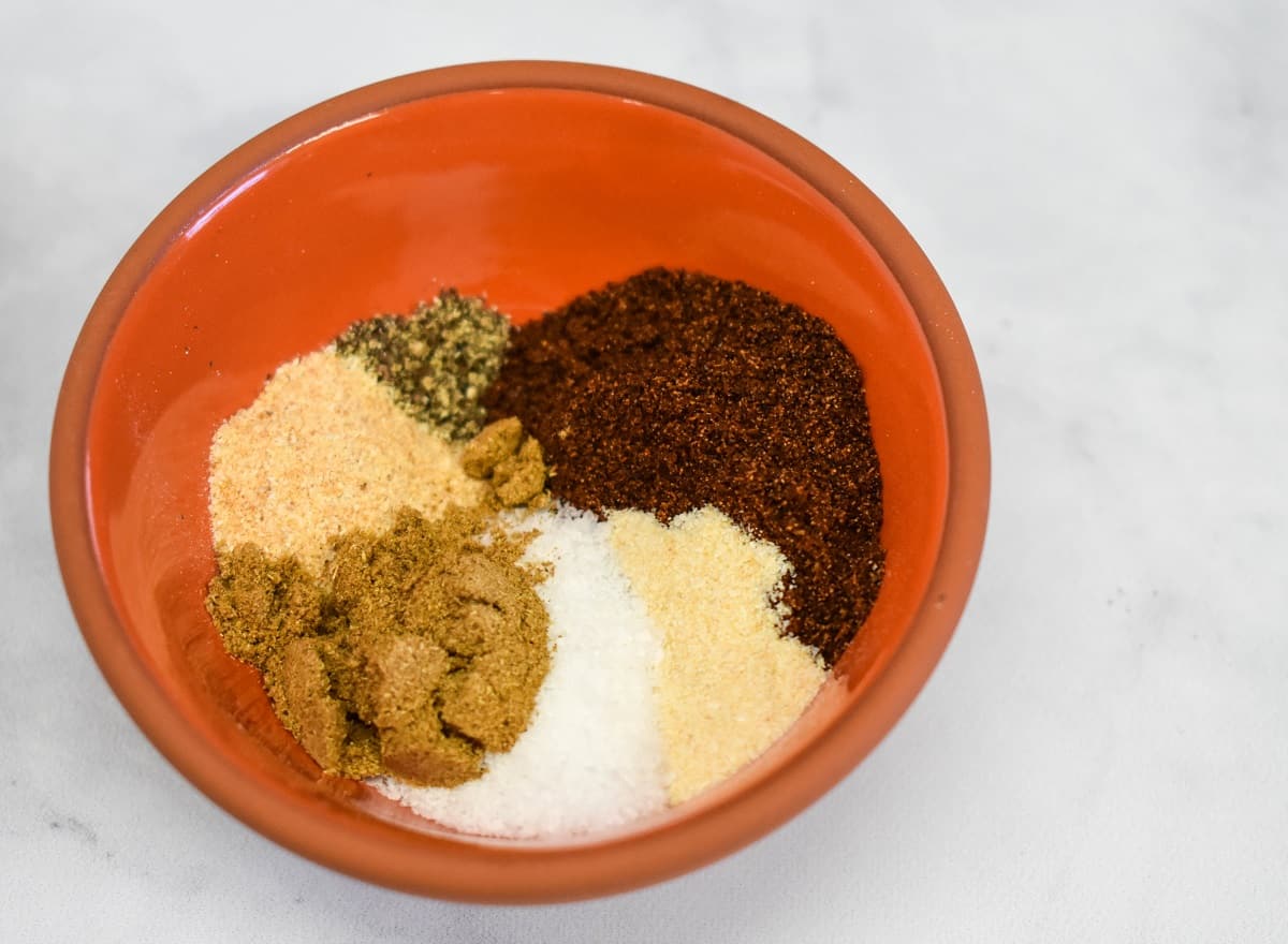 The spices in the taco seasoning in a small orange bowl before being mixed.