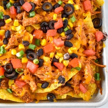 An image of the finished shredded chicken nachos on a sheet pan.
