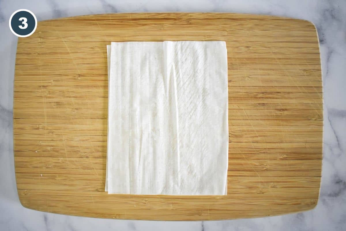Stacking the two phyllo halves on top of each other.