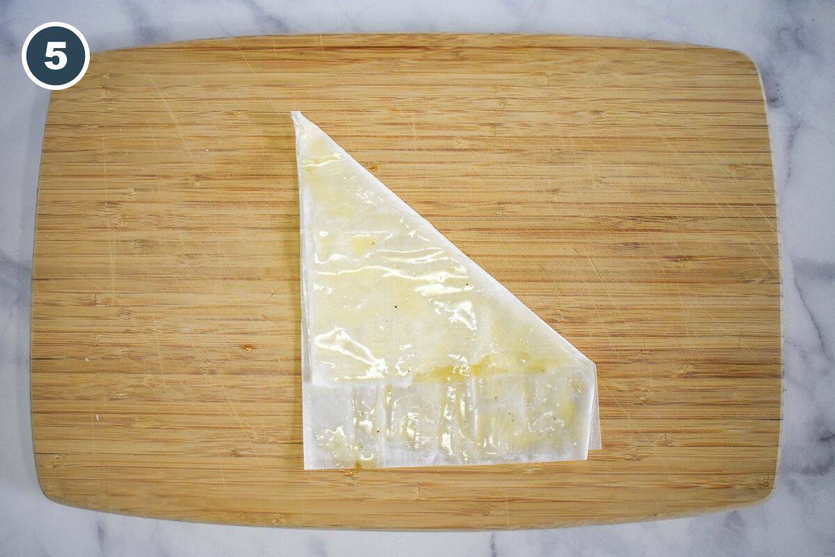 Brushing the phyllo with seasoned melted butter.