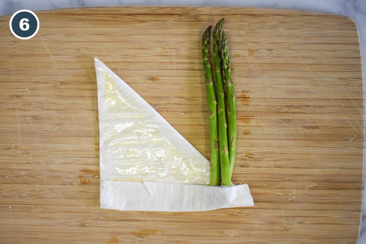 Placing three asparagus spears on the short end of the phyllo sheet.