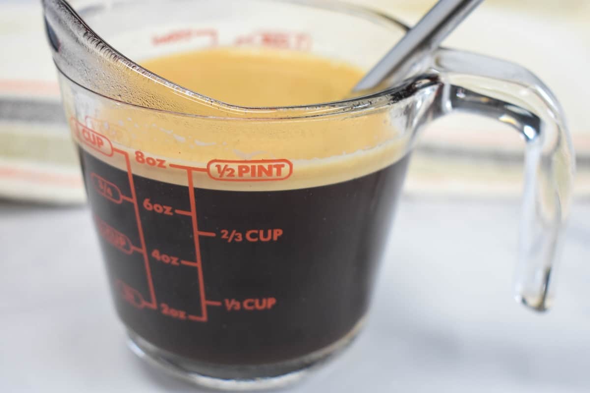 The Cuban coffee mixed with the sugar with the foam on top in a glass measuring cup.