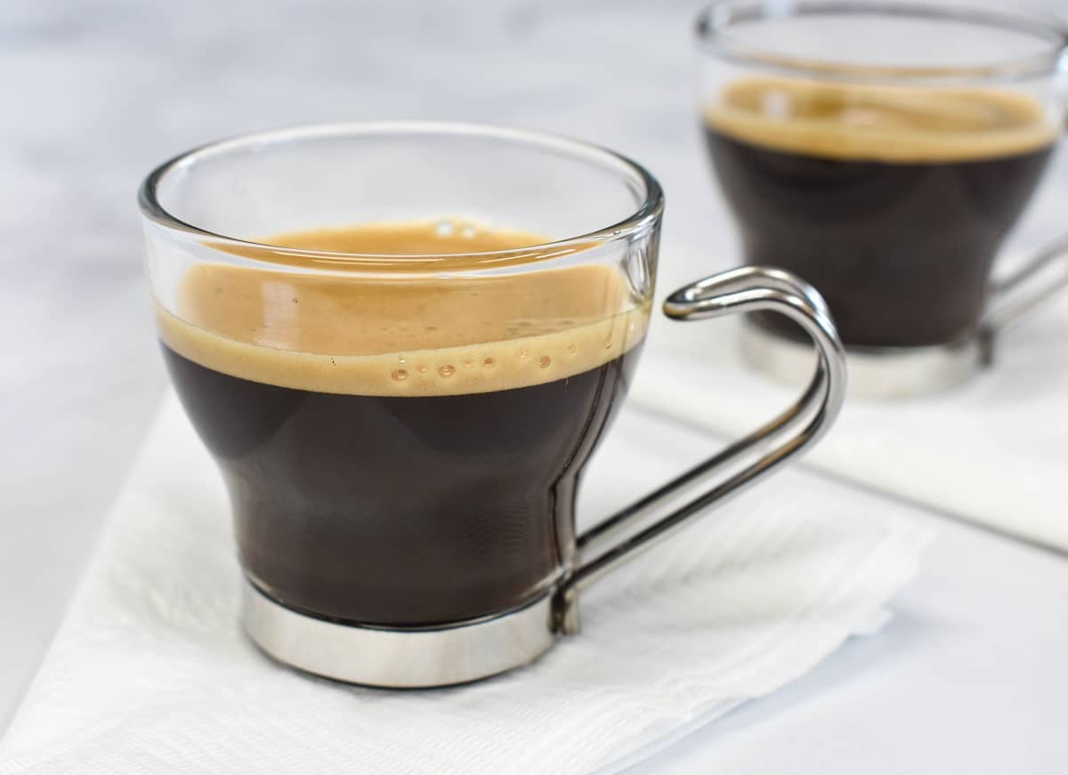 Cuban coffee served in a clear espresso cup and set on a white napkin.