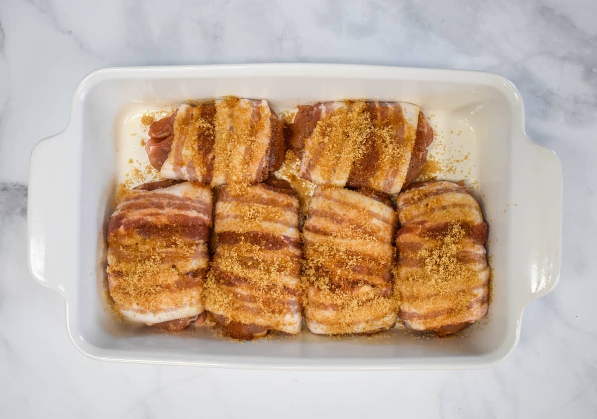 The prepped chicken arranged in a white casserole dish and set on a white table.