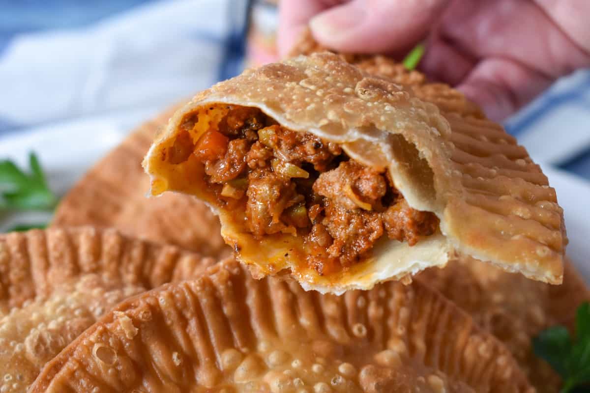 A close up of half of an empanada showing the meat on the inside.