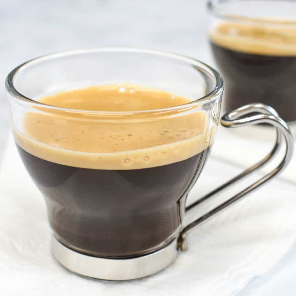 Cuban coffee served in a clear espresso cup and set on a white napkin.